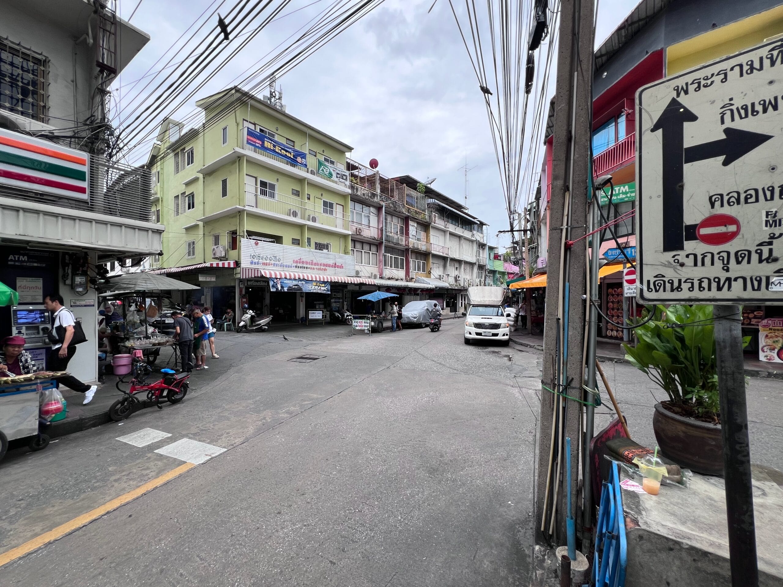Cross roads in the backstreets of Bangkok with street vendors and shops.
