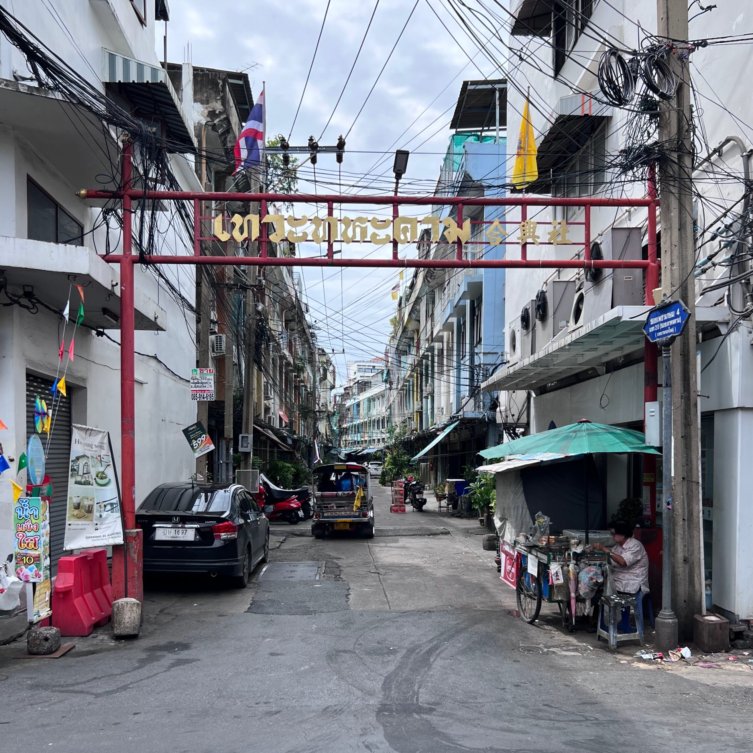 Narrow Bangkok street with small businesses, shops and residential buildings