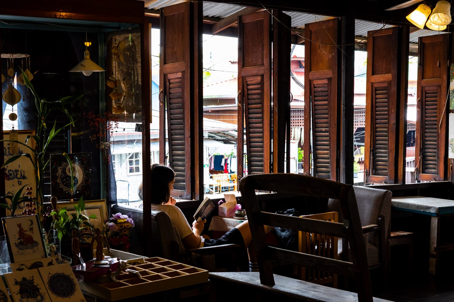 A woman relaxes while reading a book on the top floor of the Artist House Bangkok
