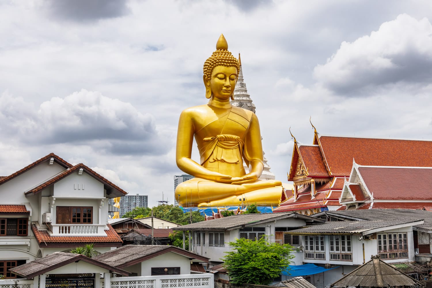 Huge golden buddha towering above nearby Thon Buri streets in Bangkok.