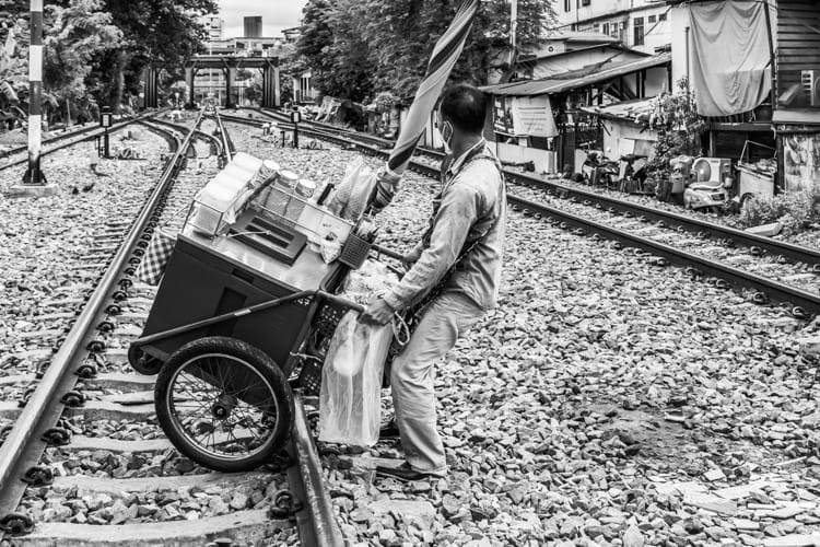 A man struggles to pull a cart over railway tracks near Saen Saep Canal in Bangkok