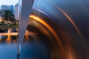 The metal sides of a walkway in a city appear curved and colourful