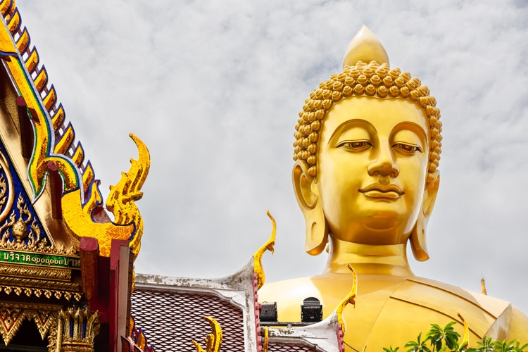 The giant golden Buddha in Bangkok towers over nearby temple roofs