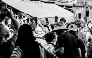 A crowd holding mobile phones up to photograph the Mae Klong railway market train
