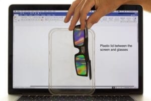 Colourful patterns in a plastic lid between a laptop screen and some 3-D polarising glasses