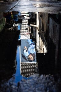 Low-level view of a reflection in a puddle of the Ghost Tower, Bangkok, showing an advert of a young girl wearing boxing gloves