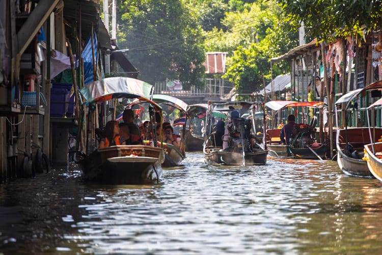 Boats on the canal at Khlong Lat Mayom floating market in the afternoon sun.