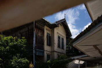 An old wooden mansion in Bangkok old town seen between overlapping roofs